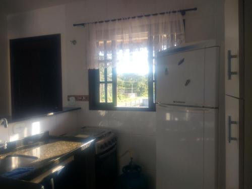 een keuken met een witte koelkast en een raam bij RESIDENCIAL CANTINHO PANTANEIRO in Itapoa