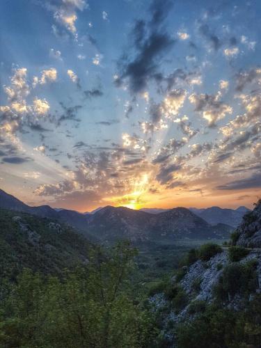 a sunset over a mountain range with the sun setting at Apartments "Old house Pajovic" in Virpazar