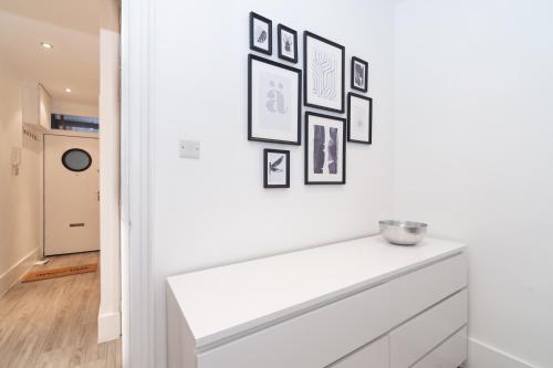 a white dresser in a room with pictures on the wall at New 2 Bed Apartment in Covent Garden in London