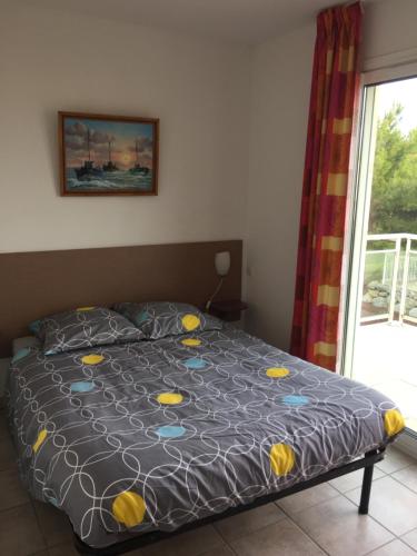 um quarto com uma cama com um edredão azul e amarelo em T 3 appart les jardins du phœbus em Gruissan