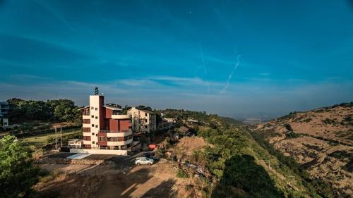 a building on top of a hill next to a mountain at Pooja Villa Suites-Rooms and Pool, Igatpuri in Igatpuri