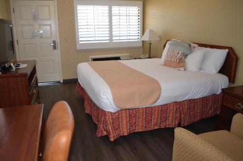 a hotel room with a large bed and a chair at Valley Inn San Jose in San Jose