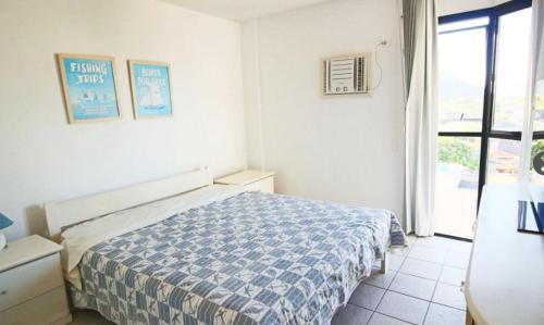 a bedroom with a bed with a blue and white comforter at Cobertura Duplex perto do mar, piscina, linda vista, 03 garagens, churrasqueira in Guaratuba