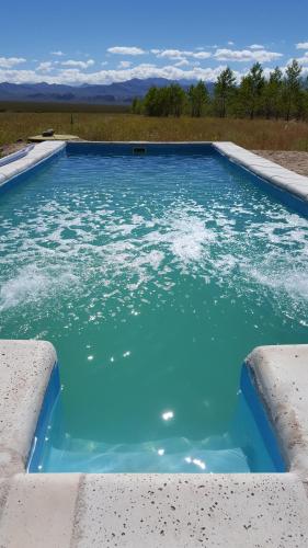a swimming pool with blue water in a field at Hotel boutique Pukarainca in Uspallata