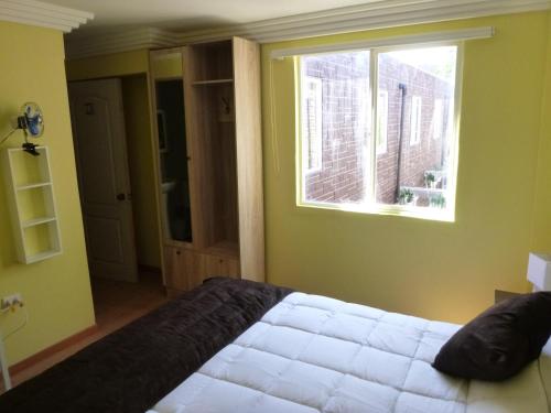 a bedroom with a white bed and a window at Hotel Barrio Yungay in Santiago
