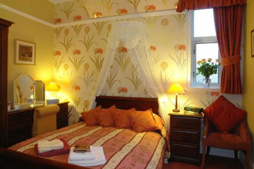 a bedroom with a bed and a chair and a window at Midway Guest House in York