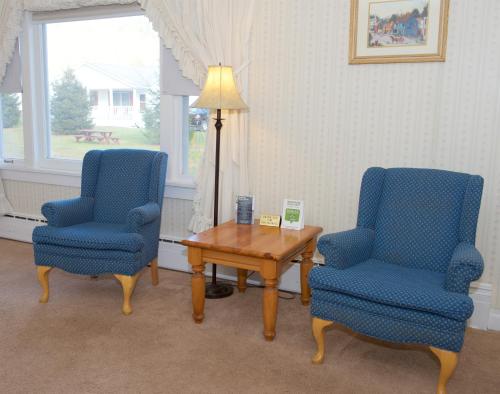 a room with two chairs and a table and a lamp at Myer Country Motel in Milford