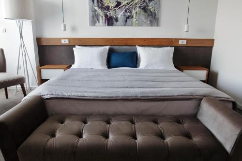 a large bed with a brown couch in a bedroom at New City Hotel & Restaurant Niš in Niš
