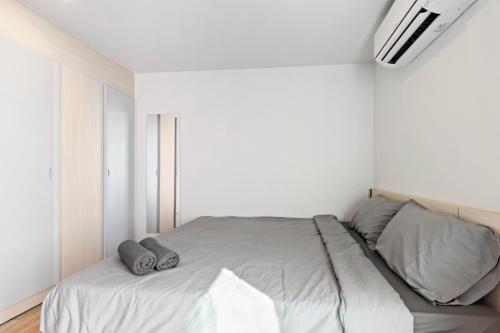 a white bedroom with a bed with two gray pillows at Nidhra นิทรา in Ban Lat Krachaeng