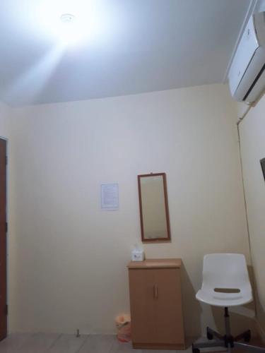 a white room with a mirror and a chair at Jakson Homestay in Batam Center