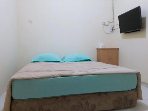 a bed with two blue pillows in a room at Jakson Homestay in Batam Center