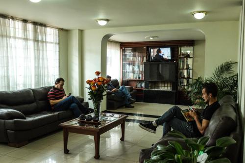 three people sitting on a couch in a living room at Apartamentos Galerías in Bogotá