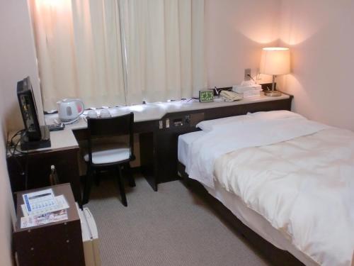 a hotel room with a desk and a bed at Tsuyama Central Hotel Townhouse in Tuyama