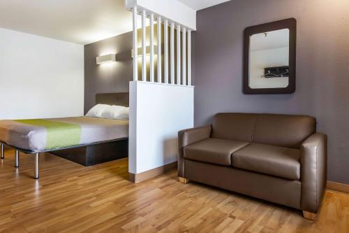 Habitación con cama, sofá y espejo. en Studio 6-Alexandria, LA, en Alexandria