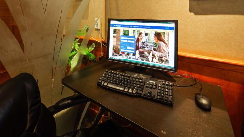 a computer monitor and a keyboard and mouse on a table at Best Western Queens Court in Queens