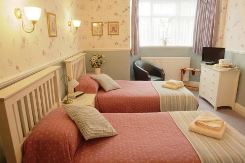 a room with three beds and a desk and a television at Midway Guest House in York