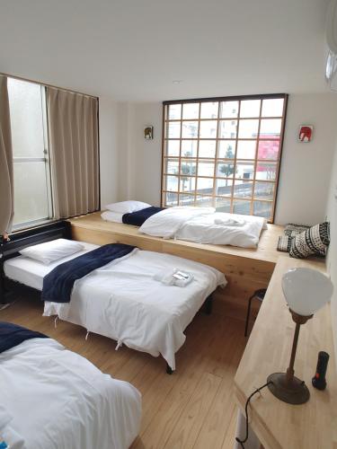 pokój z 3 łóżkami i 2 oknami w obiekcie 駐車場無料 Nagoya Hostel The Three Smiles Free Car Park w mieście Nagoja
