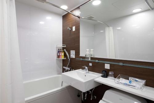 a bathroom with a sink and a tub and a mirror at Comfort Hotel Kochi in Kochi