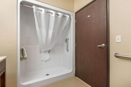 El baño incluye una ducha blanca con cortina. en Comfort Suites en Cedar Falls
