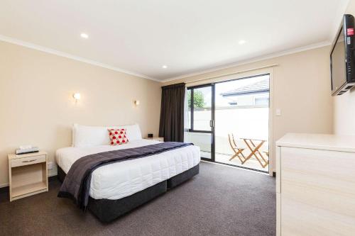 a hotel room with a bed and a balcony at Kauri Court Motel and Apartments in Palmerston North