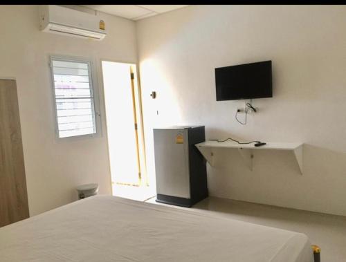 um quarto com uma cama e uma televisão na parede em SKF Apartment em Sakon Nakhon