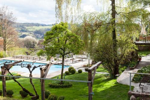 a pool in a park with benches and trees at Hotel Heubad in Fiè
