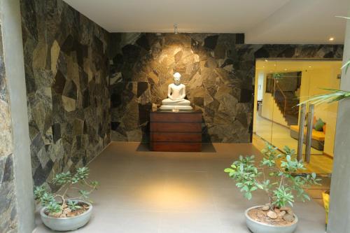 a statue in a room with two potted plants at Lotus Lake Residence in Kandy