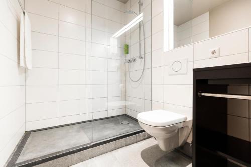 La salle de bains blanche est pourvue d'une douche et de toilettes. dans l'établissement RiKu HOTEL Neu-Ulm, à Neu-Ulm