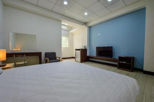 a bedroom with a large white bed and a tv at Ta Li Wen B&B in Zhushan