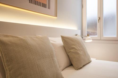 a white couch with two pillows and a window at Gran Central Suites in Madrid