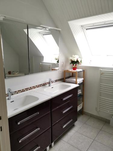 une salle de bain avec deux lavabos et un grand miroir dans l'établissement la frégate blanche, à Concarneau