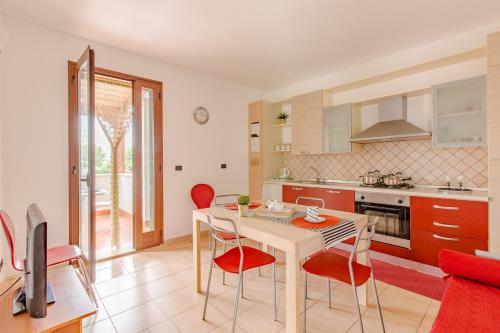a kitchen with a table and red chairs in a room at Appartamento prato inglese sinistro Salento in Specchiolla 