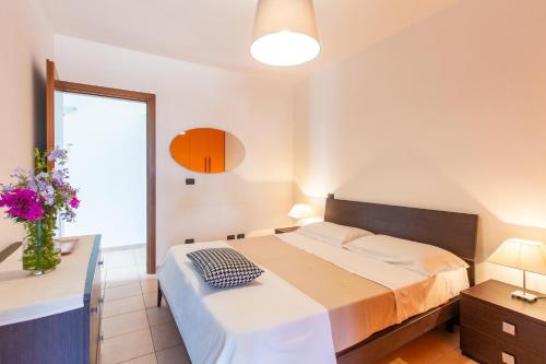 a bedroom with a bed and a vase of flowers at Appartamento prato inglese sinistro Salento in Specchiolla 