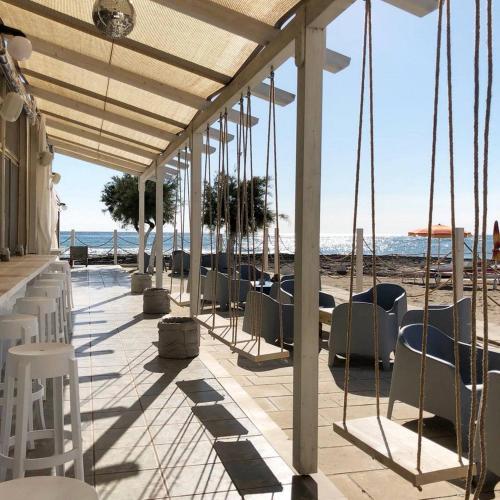 a patio with chairs and tables on the beach at Appartamento prato inglese sinistro Salento in Specchiolla 
