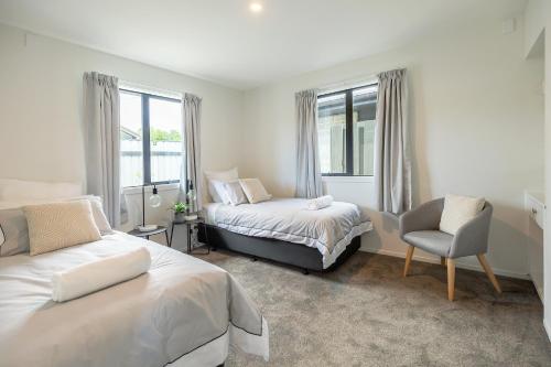 a bedroom with two beds and a chair and window at The Willows Wanaka in Wanaka