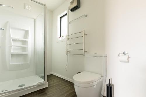 a white bathroom with a toilet and a shower at The Willows Wanaka in Wanaka