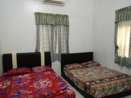 two beds sitting in a room with windows at Aiman Homestay in Marang