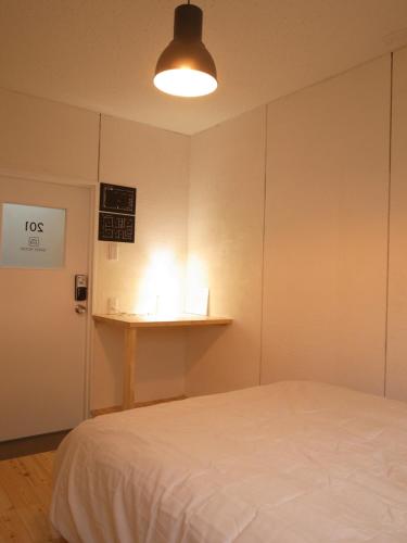 a bedroom with a bed and a light on the wall at Guesthouse Banvina in Kagoshima