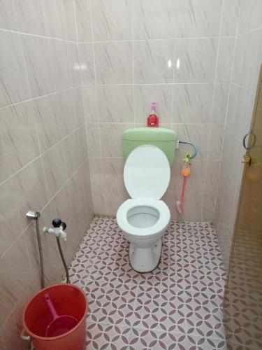 a bathroom with a green toilet and a bucket at Aiman Homestay in Marang