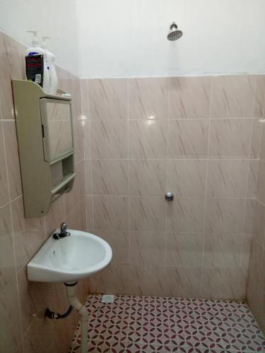 a bathroom with a sink and a tiled wall at Aiman Homestay in Marang