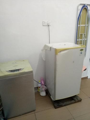 a small refrigerator and a washing machine in a room at Aiman Homestay in Marang