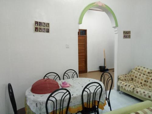 a dining room with a table and chairs and a couch at Aiman Homestay in Marang