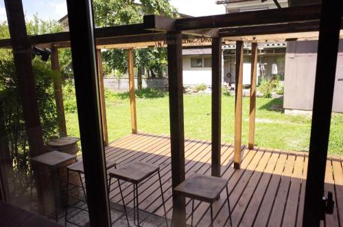 a screened in porch with stools on it at 古民家ゲストハウス ナマケモノ in Ōno