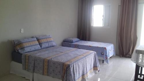 sypialnia z 2 łóżkami pojedynczymi i oknem w obiekcie Suíte Triplex w mieście Capitólio