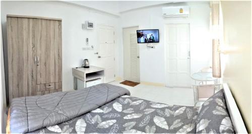 um quarto com uma cama e uma televisão na parede em Baankanjana em Hat Yai