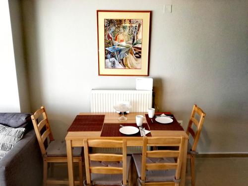 einen Esstisch mit 4 Stühlen und ein Gemälde an der Wand in der Unterkunft Spacious and Modern Downtown Apartment in Iraklio