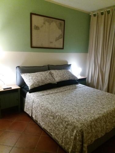 Ce lit se trouve dans une chambre dotée de murs verts et de 2 tables. dans l'établissement Casa Camilla, à Viareggio