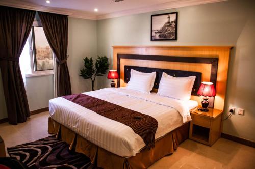 a bedroom with a large bed with two lamps at Shally Residence 3 in Al Khobar