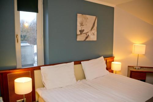 1 dormitorio con 1 cama con sábanas blancas y 2 lámparas en Old Lake Golf Hotel, en Tata