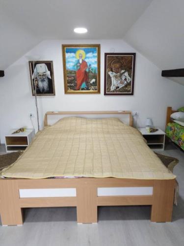 a bed in a bedroom with pictures on the wall at Apartman Vrdničak in Vrdnik